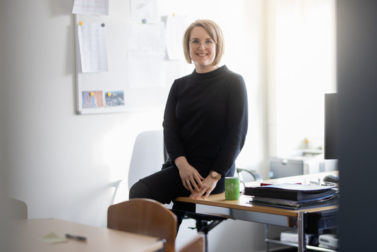 Dr. Hanna Altmeppen sitzt auf der Tischkante ihres Schreibtischs.