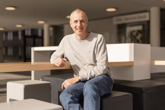 Arne von Irmer sitzt auf einem Hocker im Foyer des ITMC-Gebäudes.